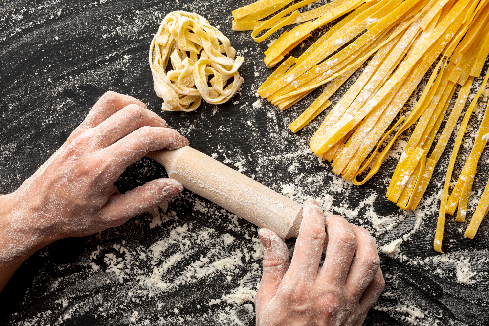 chef holding rolling pin near pasta